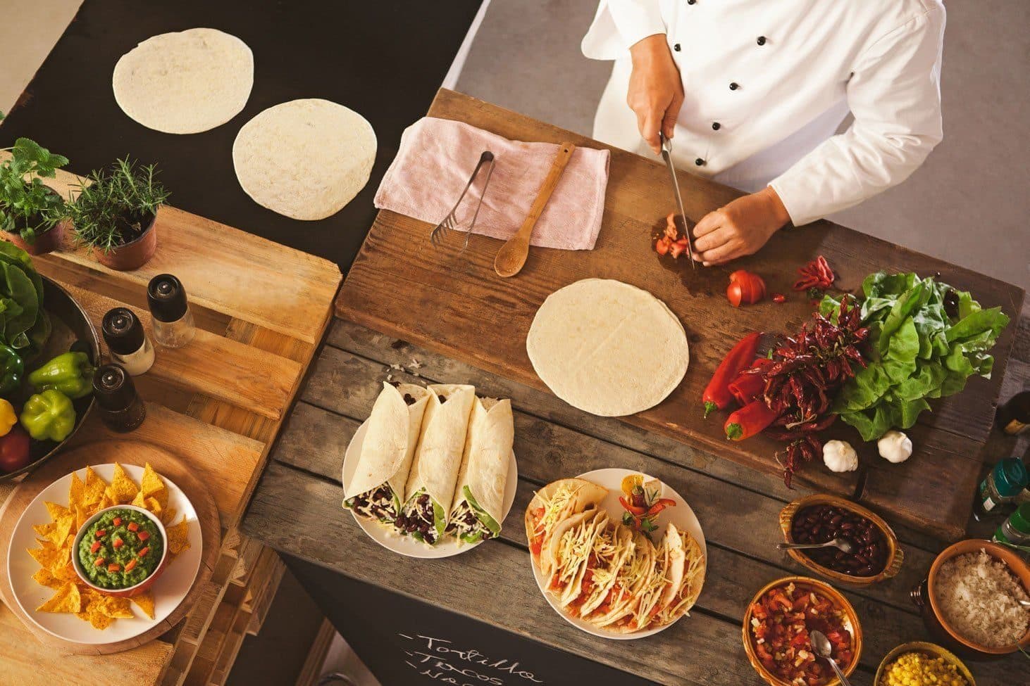 A chef assembling tacos on a wooden board